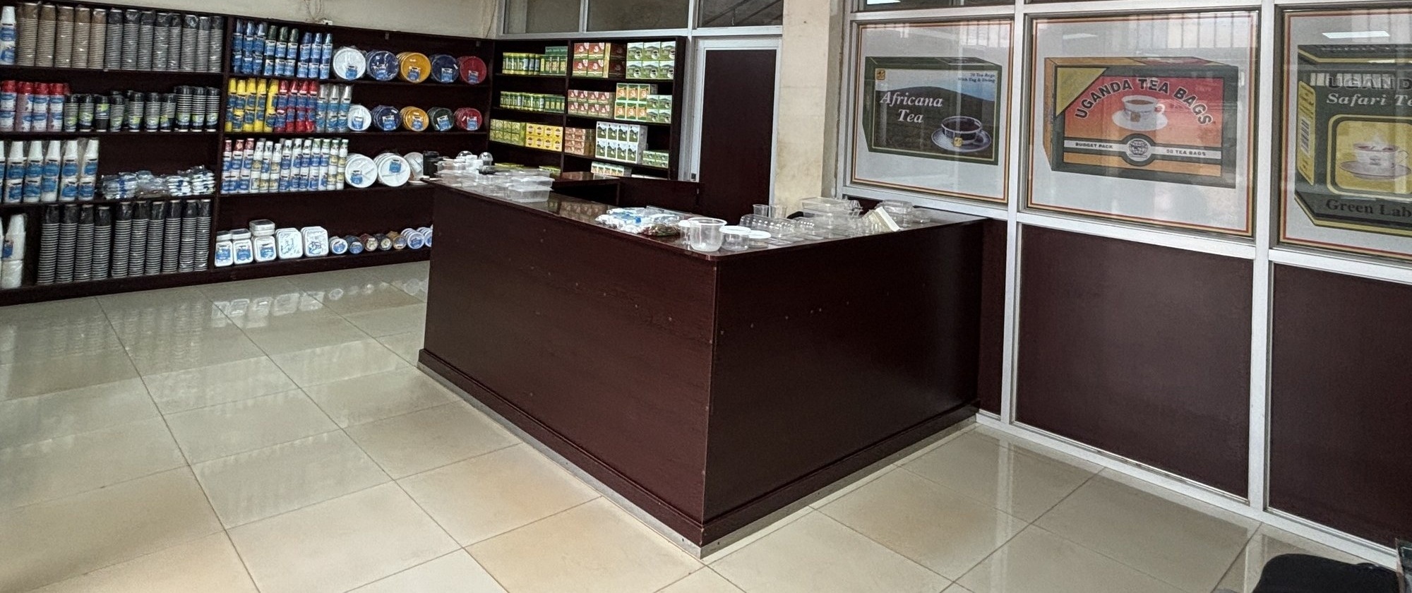 Eagle Holdings store interior — counter, shelves of coffee cups, and framed Africana, Uganda Tea Bags and Safari brand displays